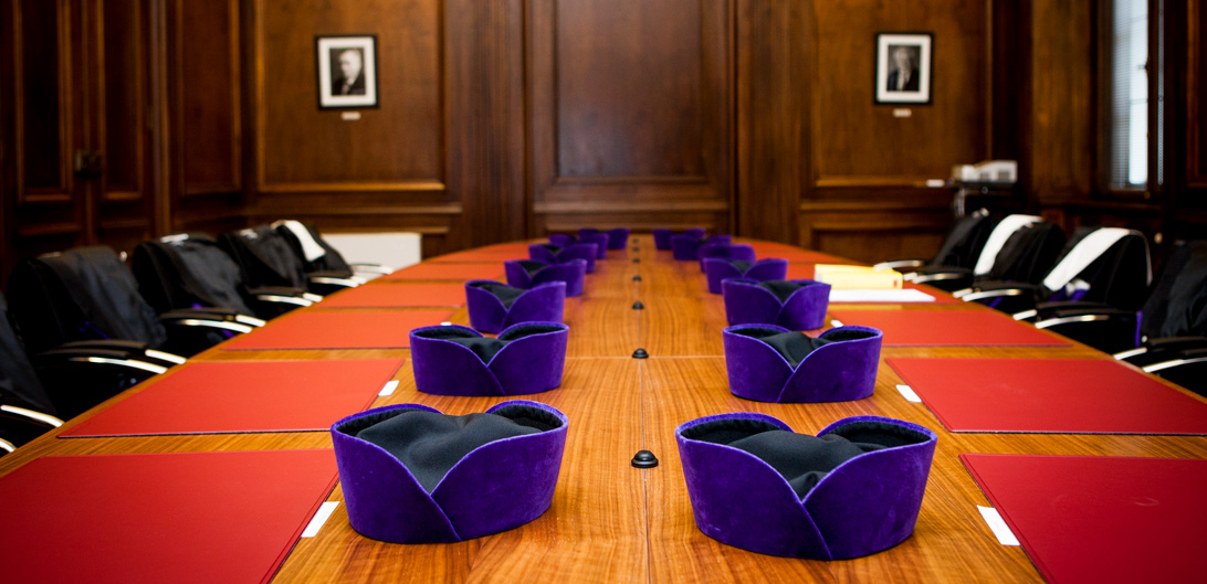 Tisch im Beratungszimmer 2 mit den Baretten der Verfassungsrichterinnen und -richter
